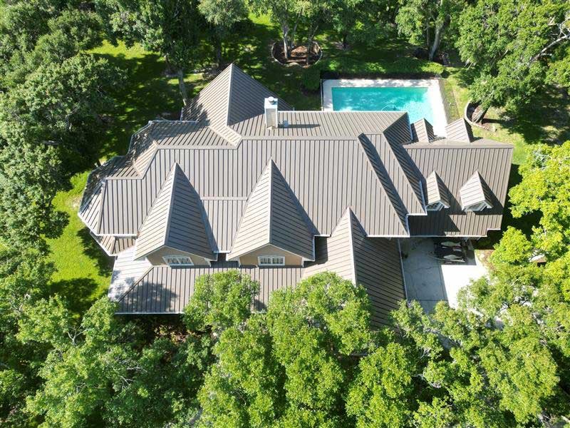 Aerial of a standing-seam metal roof on a custom Odessa home with a pool